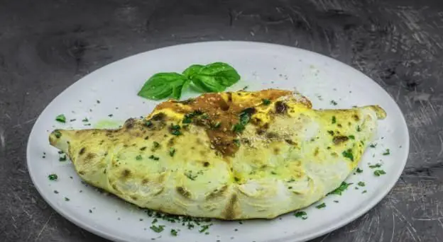 کالزونه ایتالیایی سنتی و خانگی بونو با خمیر نازک، پنیر موزارلا، سس مخصوص و برگ‌های معطر ریحان برای یک وعده فراموش‌نشدنی.