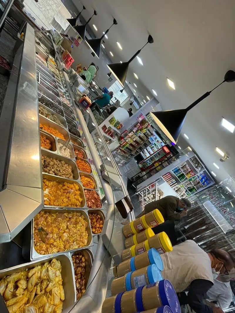 سوپر پروتئین ملل: ویترین‌های بزرگ حاوی مرغ و گوشت طعم‌دار، خورشت و انواع فرآورده‌های پروتئینی تازه، همراه با مشتریان در حال انتخاب محصول.