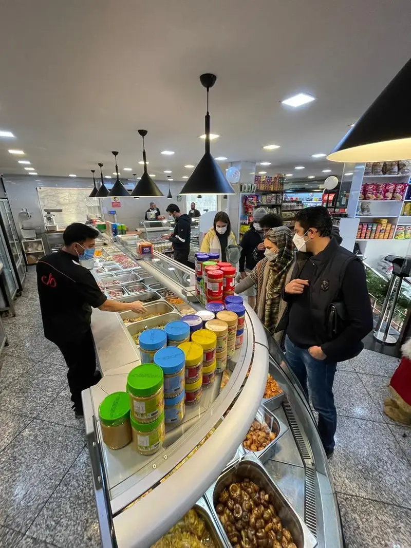 فروشگاه سوپر پروتئین ملل با پیشخوان جذاب انواع محصولات پروتئینی، فرآورده‌های تازه و غذاهای آماده، مشتریان در حال خرید.