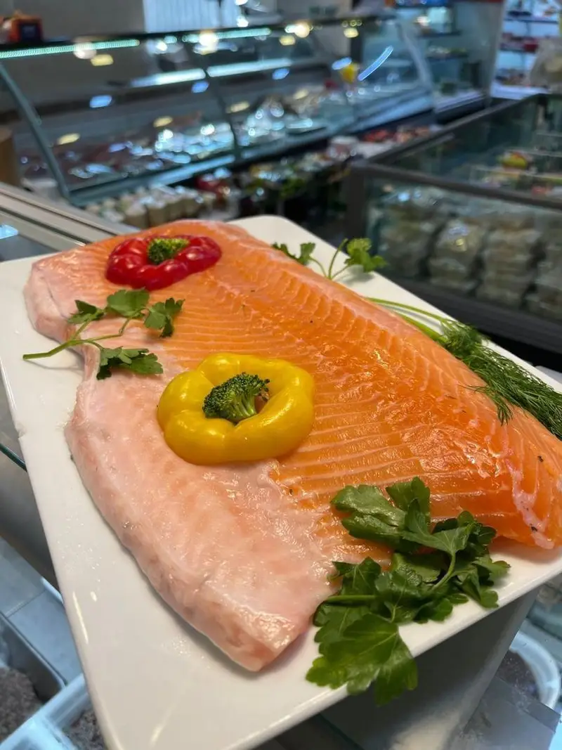 فیله ماهی سالمون تازه و باکیفیت در سوپر پروتئین ملل. غذای دریایی ممتاز، تزئین شده با فلفل دلمه ای، بروکلی و سبزیجات تازه، آماده طبخ.