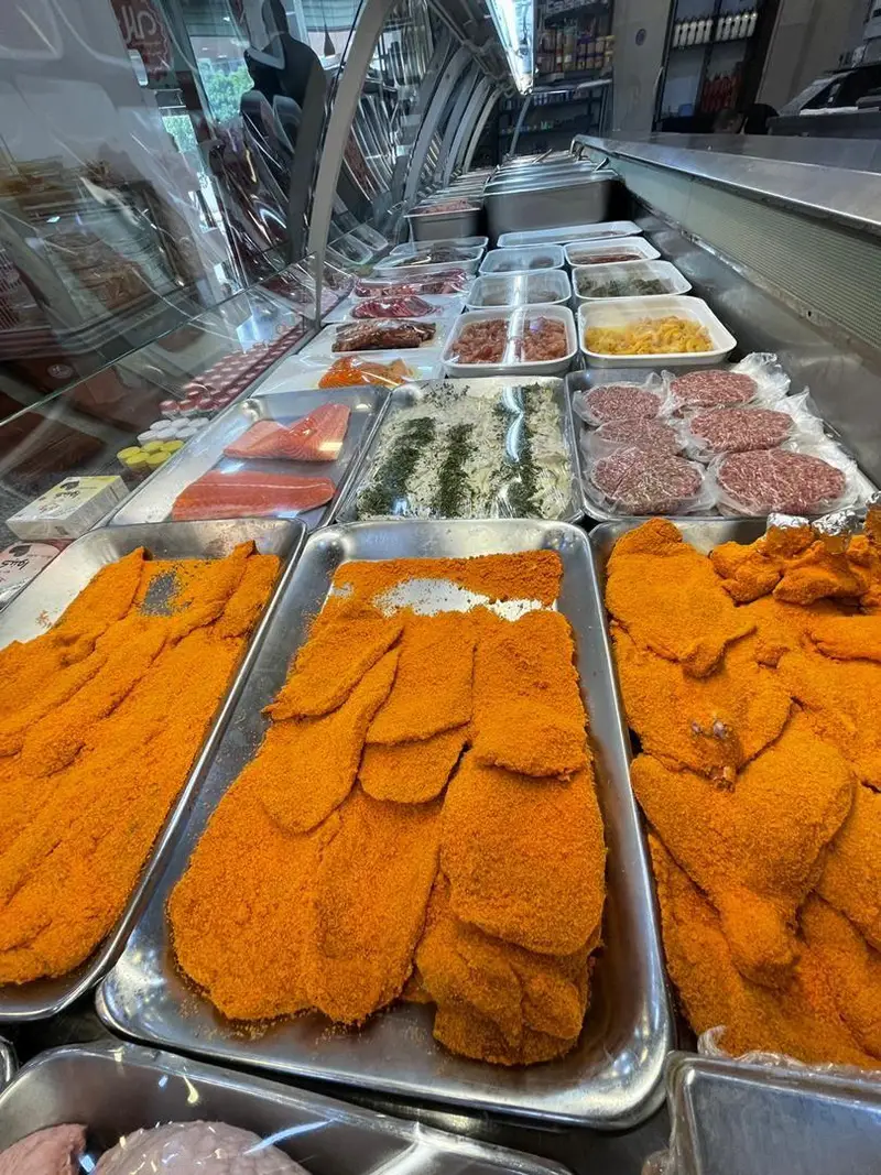 ویترین پر از محصولات پروتئینی سوپر پروتئین ملل شامل گوشت قرمز، ماهی سالمون، مرغ سوخاری، همبرگر و شنیتسل تازه و آماده.