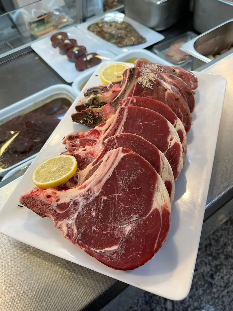 سینی بزرگ از گوشت‌های تازه و باکیفیت: شیشلیک، دنده و استیک گوسفندی آماده طبخ در سوپر پروتئین ملل برای کباب.