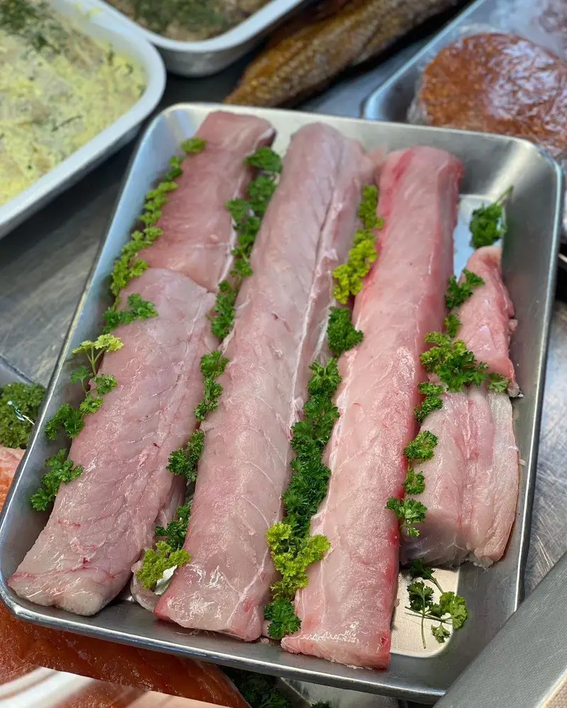 فیله‌های تازه و مرغوب ماهی با رنگ صورتی روشن، چیده شده در سینی استیل و مزین به جعفری تازه در سوپر پروتئین ملل.