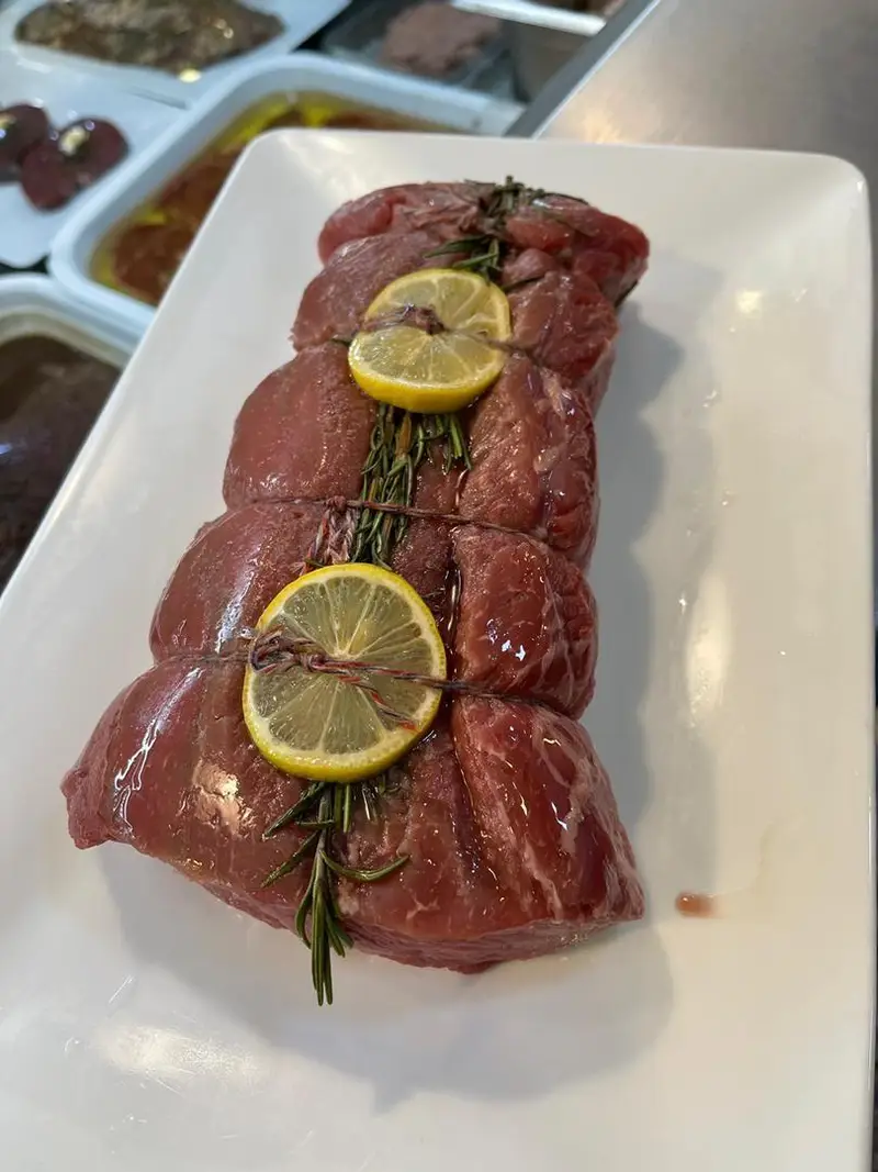 نمایی نزدیک از گوشت تازه و مرغوب آماده طبخ، تزیین شده با رزماری و لیمو، مناسب برای بهترین غذاها از سوپر پروتئین ملل.