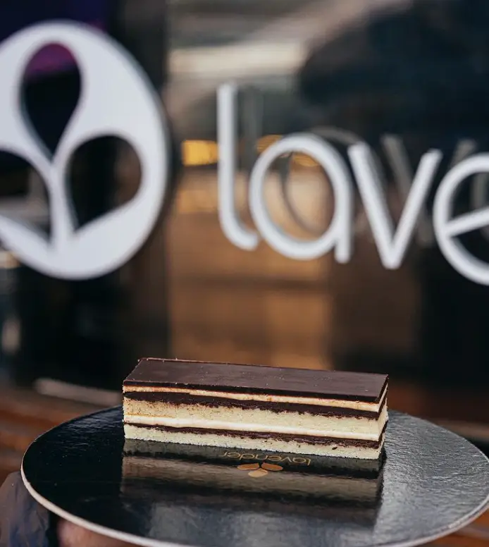 کیک لایه‌ای شکلاتی و کرم خوشمزه کافه لوندر، دسری دلپذیر و خاص برای تجربه طعمی به‌یادماندنی در محیطی گرم و دوستانه.