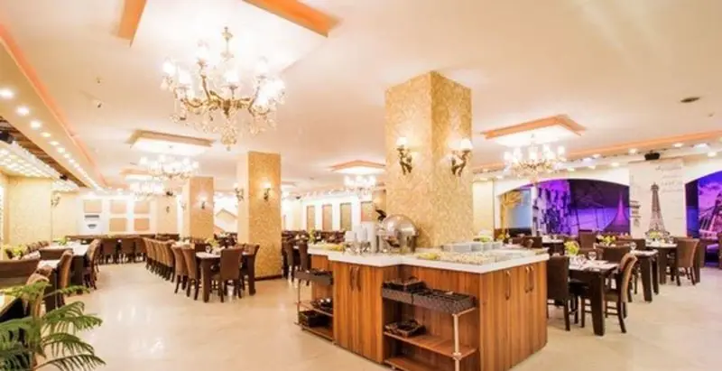 فضای داخلی لوکس رستوران کلاسیک پردیس با سالن غذاخوری وسیع، میز و صندلی‌های شیک، بوفه مدرن و لوسترهای کریستالی درخشان.