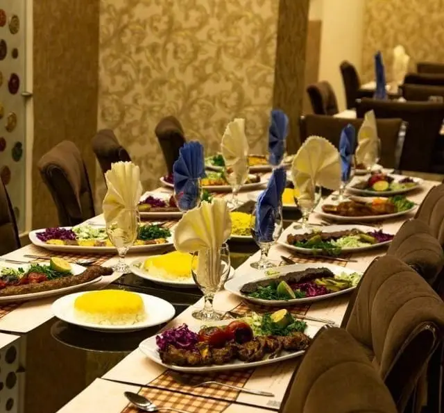 میز غذای چیده شده در رستوران کلاسیک پردیس با انواع کباب، برنج زعفرانی، سالاد و دستمال سفره‌های رنگی آماده پذیرایی.