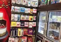 نمای داخلی فروشگاه شیرینی و آجیل گلستان، نمایشگر قفسه‌های متنوع لوازم قنادی، دکوراسیون کیک و یخچال پر از شیرینی و کیک تازه.