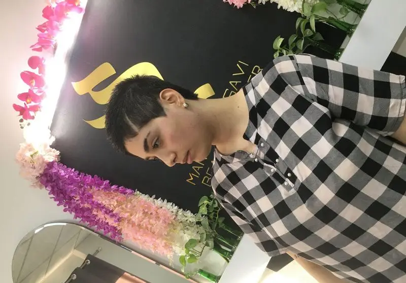 مدل موی کوتاه پیکسی و فشن زنانه در سالن زیبایی مریم موسوی با پس‌زمینه مشکی و گل‌آرایی شده به همراه لوگوی طلایی