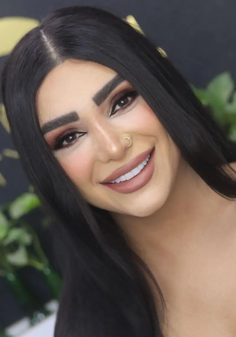 میکاپ صورت و آرایش چشم اسموکی زن جوان با موهای مشکی بلند، رژ لب نود و لبخند زیبا مناسب برای ایده آرایش عروس و مجالس