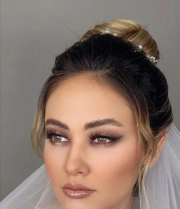 میکاپ و آرایش عروس با سایه چشم اسموکی ملایم، رژلب شاین نود و شینیون موی جمع شده همراه با تور در سالن زیبایی مریم موسوی