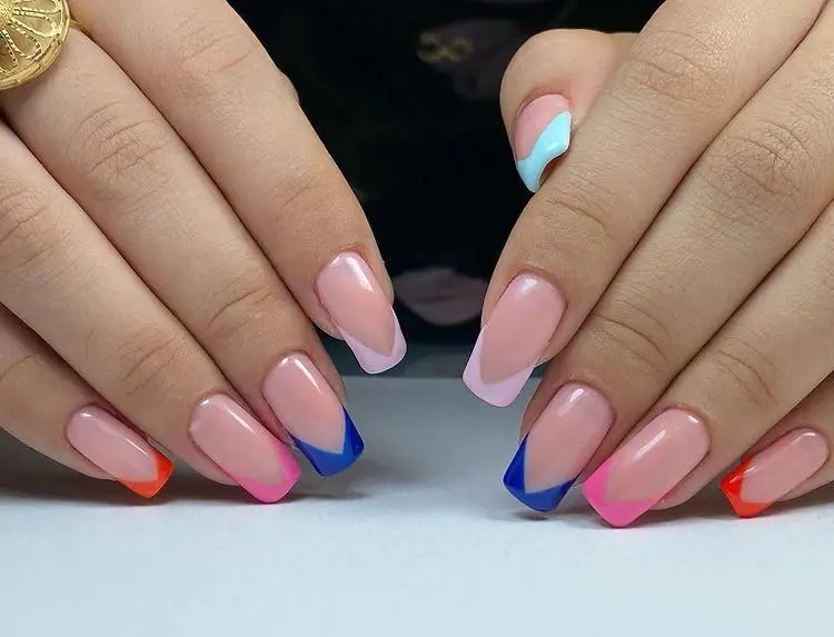 طراحی و کاشت ناخن با لاک‌های رنگی و شاد به سبک فرنچ فانتزی روی ناخن‌های دست یک خانم در مرکز تخصصی زیبایی مریم موسوی