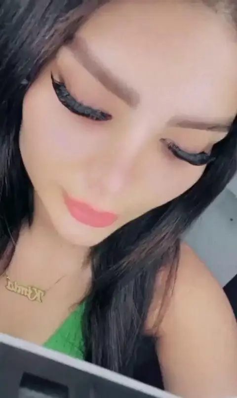 آرایش صورت دخترانه با خط چشم گربه‌ای پهن و مشکی، مژه‌های پرپشت، رژ لب صورتی ملایم و گردنبند طلایی اسم روی گردن