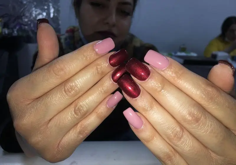 طراحی و کاشت ناخن با ترکیب رنگ های صورتی ملایم و زرشکی اکلیلی شیک و جذاب مناسب برای مجالس در سالن زیبایی تخصصی