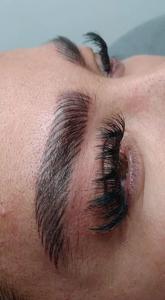 تصویر کلوزآپ و نمای نزدیک از مژه‌های مشکی اکستنشن شده و فیبروز ابروی زنانه انجام شده در خدمات مرکز زیبایی مریم موسوی
