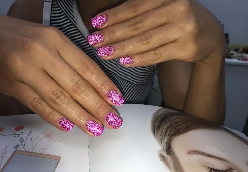 طراحی ناخن شیک و بسیار جذاب با لاک صورتی اکلیلی درخشان و زیبا مناسب برای مجالس و مهمانی‌ها در سالن تخصصی کاشت ناخن