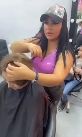 آرایشگر حرفه‌ای زنانه با کلاه در حال کوتاه کردن و استایل دادن به موهای مشتری در سالن زیبایی و خدمات تخصصی هیرکات مو