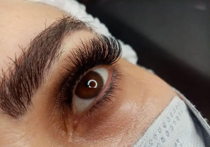 عکس نزدیک از اکستنشن مژه والیوم مشکی، ضخیم و بسیار پرپشت روی چشم قهوه‌ای مشتری در سالن آرایش و مرکز زیبایی مریم موسوی