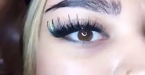 عکس نزدیک از کاشت مژه والیوم و اکستنشن مژه بلند دخترانه با طراحی خاص و رنگی در گوشه چشم برای آرایش چشم حرفه‌ای و زیبا