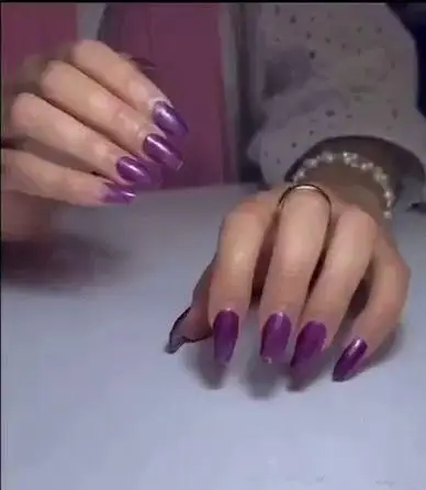 کاشت ناخن حرفه‌ای و ژلیش با لاک ژل بنفش بادمجانی براق و بسیار شیک روی ناخن‌های بلند و کشیده زنانه در سالن زیبایی