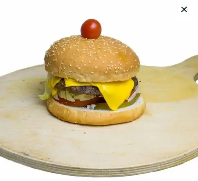 همبرگر خوشمزه با پنیر ذوب شده، کاهو و گوجه روی تخته چوبی، بهترین انتخاب برای سفارش از فست فود شبانه.