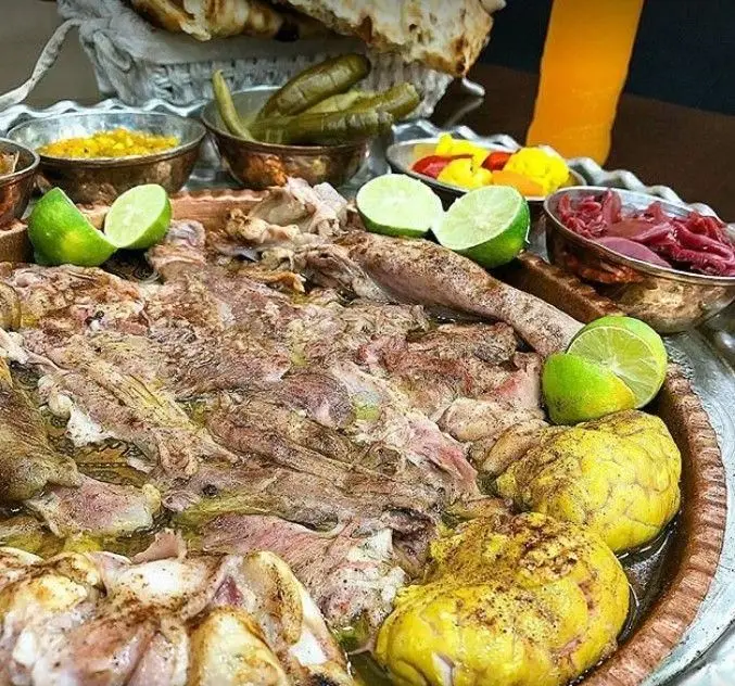 سینی پر از گوشت پخته شده و آبدار طباخی چیذر همراه با لیمو، ترشی و کاسه‌های احشاء؛ یک وعده غذای سنتی ایرانی.