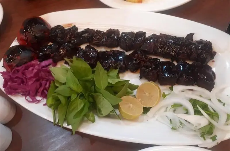 سینی کباب دل و جیگر سنتی رستوران ایرانی عمارت با گوجه کبابی، کلم قرمز، سبزیجات معطر، پیاز، جعفری و لیمو تازه، غذای اصیل.