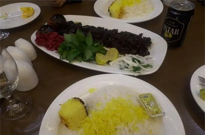 میز شام/ناهار در رستوران ایرانی عمارت با چلوکباب مجلسی، برنج زعفرانی، ته دیگ، سبزیجات تازه و نوشیدنی ایستک.