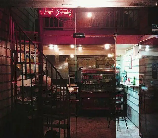 پیتزا پل: نمایی از ورودی رستوران در شب، با تابلوی نئون درخشان، پله‌های جذاب و دکوراسیون داخلی دنج و دلنشین.