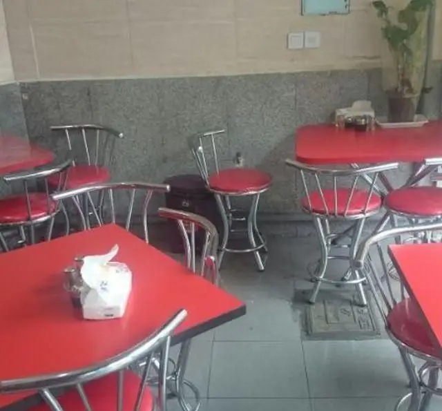 فضای داخلی چلو کبابی باباعباس، شامل میز و صندلی‌های مدرن قرمز و استیل، محیطی دنج و تمیز برای تجربه لذیذترین چلوکباب‌ها.