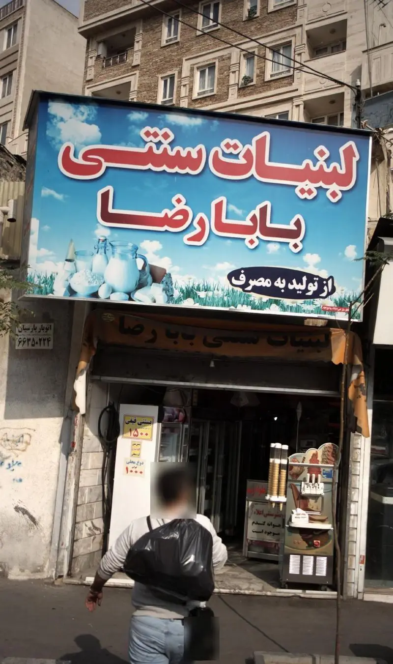 نمایی از مغازه لبنیات سنتی بابا رضا با تابلوی بزرگ و جذاب محصولات تازه لبنی از تولید به مصرف. همچنین بستنی و دوغ محلی نیز ارائه می‌شود.