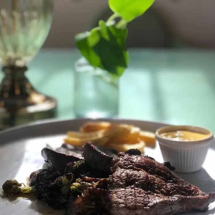 استیک آبدار با سیب‌زمینی سرخ کرده، سبزیجات رست‌شده و سس مخصوص، در فضایی دلنشین کافه سینان برای یک وعده غذایی لذیذ.