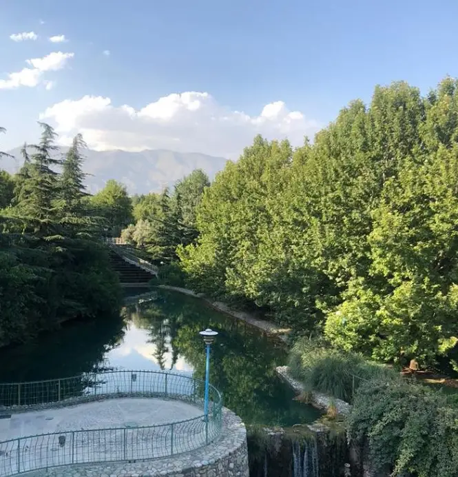 فضای سرسبز و آرامش‌بخش کافه سینان با آب جاری، درختان بلند و نمایی از کوهستان؛ مکانی دلنشین برای استراحت و لذت بردن از قهوه.