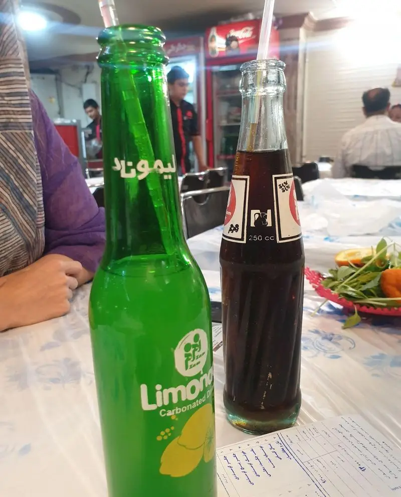 بطری‌های نوشیدنی خنک لیموناد و زم زم با نی روی میز، انتظار مشتریان را در فضای دلنشین جگرکی پرسپولیس می‌کشند.