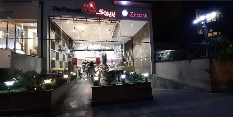 نمای شبانه و روشن رستوران فست فود پرپروک و ژوزاک. ورودی مدرن با نورپردازی زیبا، پذیرای مشتریان در محیطی دلنشین.