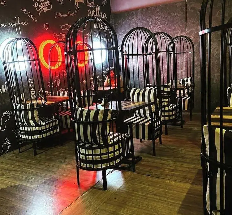 دکوراسیون داخلی کافه رستوران پرشین با صندلی‌های قفسی سیاه و سفید، میزهای چوبی و نورپردازی جذاب نئونی، محیطی خاص و دلنشین برای مشتریان.