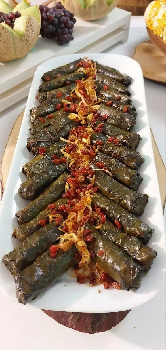 دلمه برگ مو خوش‌رنگ و لعاب با زرشک و پیاز داغ، غذای اصیل ایرانی در منوی گروه تشریفاتی لیمون برای پذیرایی از مهمانان شما.