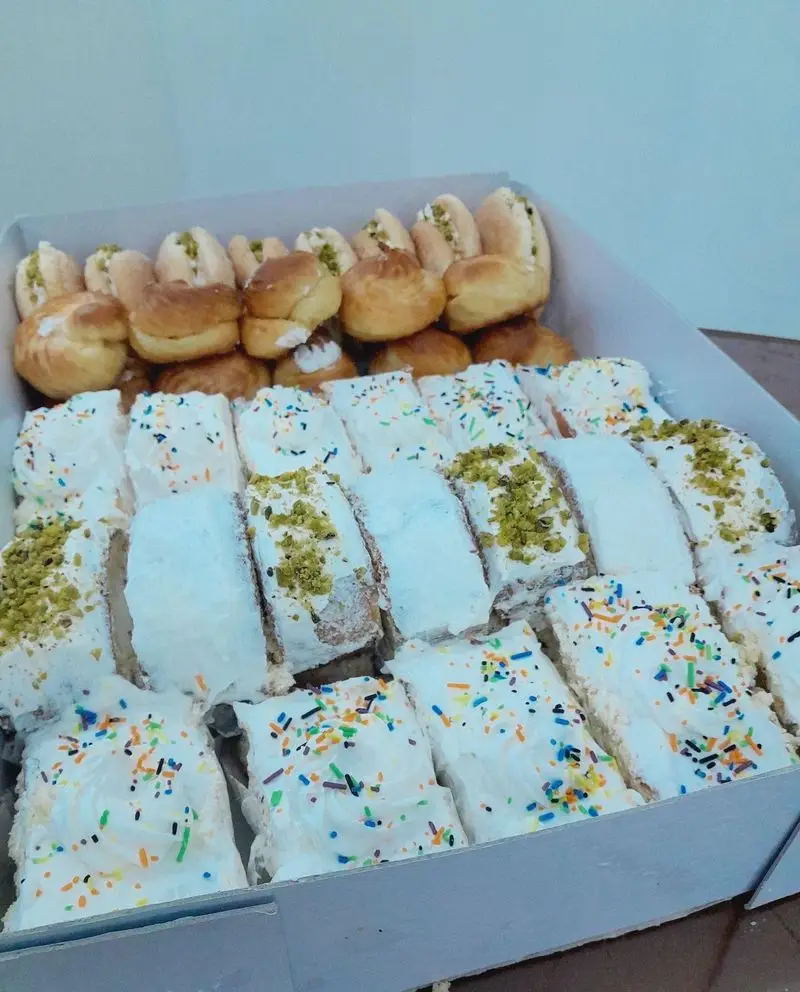 باکس متنوع شیرینی و دسر از گروه تشریفاتی lemon شامل کرم پاف، شیرینی‌های پسته ای و کیک برش خورده با تزیین پسته و اسپرینکل برای پذیرایی شیک.