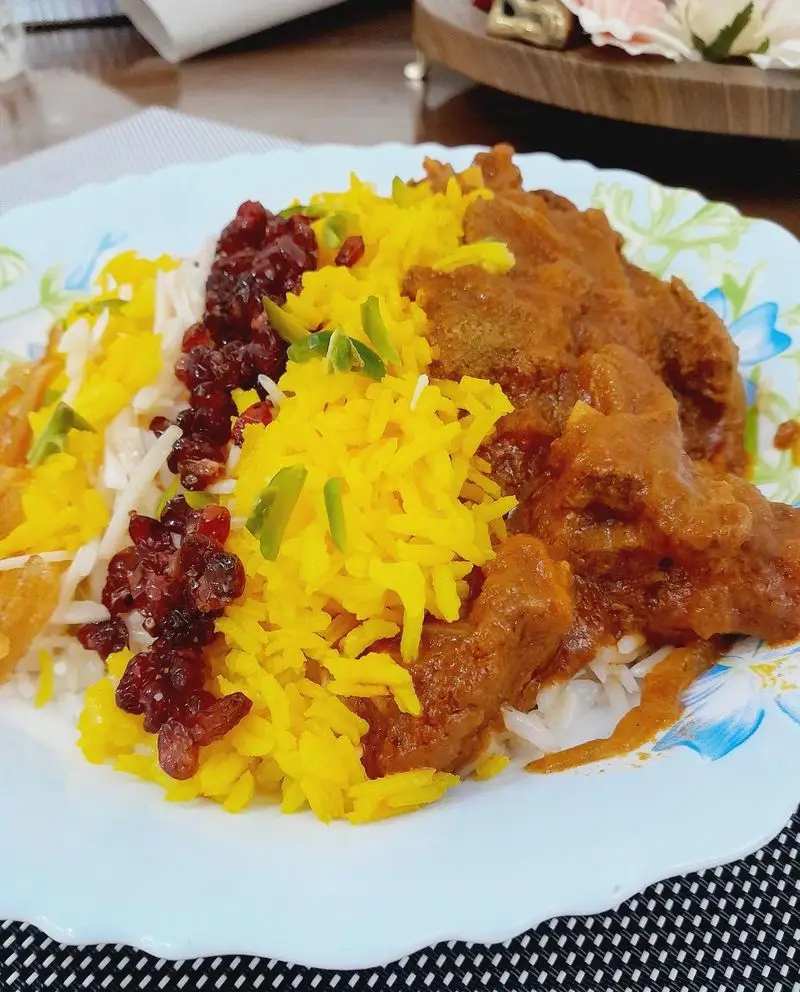 بشقاب غذای ایرانی مجلسی از گروه تشریفاتی lemon: زرشک پلو زعفرانی، برنج سفید و خورشت گوشت باکیفیت برای پذیرایی خاص مجالس و مراسم شما.