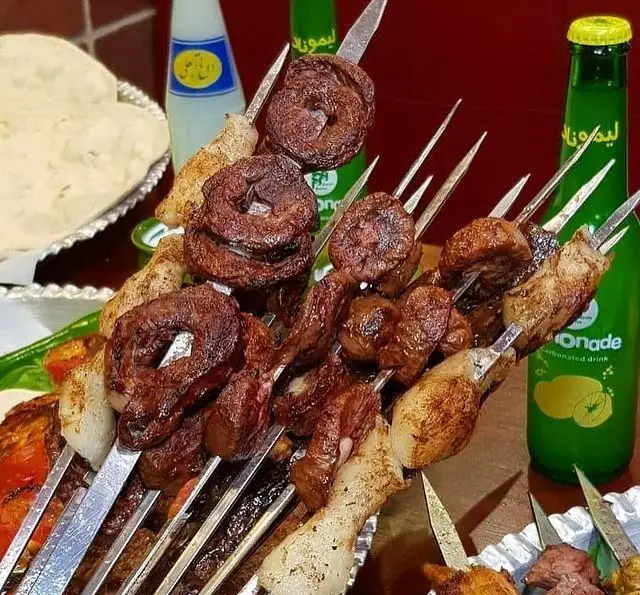 میز پر از سیخ‌های کباب جگر، دل، قلوه و مرغ با نان و نوشابه لیموناد در جگرسرای امیرخان (گل یخ).