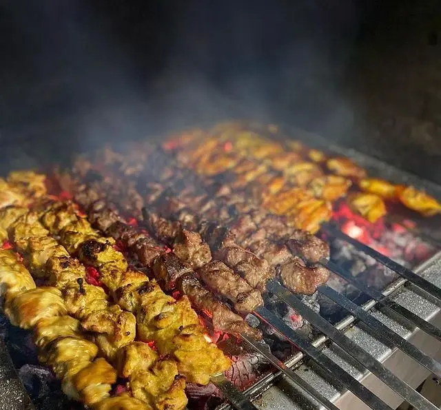 منظره‌ای دلنشین از کباب‌های گوشت و جوجه در حال آماده‌سازی بر روی ذغال داغ در جگرسرای امیرخان (گل یخ) با کیفیت عالی.
