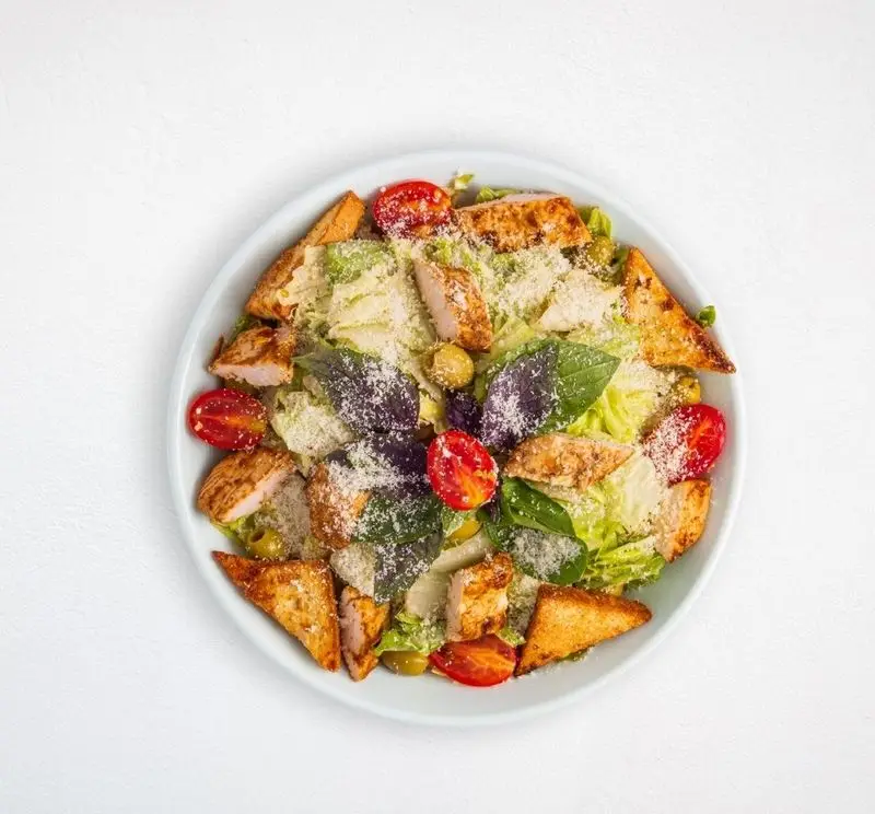 سالاد سزار مرغ گریل شده تازه و خوشمزه از هایپر کترینگ چامه، شامل کاهو، گوجه گیلاسی، زیتون، نان تست و پنیر پارمزان.