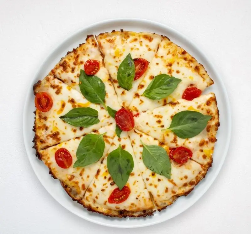 پیتزا مارگاریتا برش خورده هایپر کترینگ چامه با پنیر، گوجه گیلاسی و ریحان تازه؛ انتخابی عالی از منوی فست فود فرنگی.