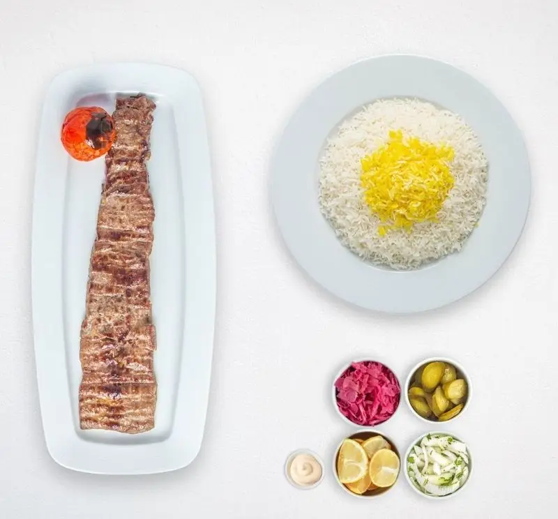 یک پرس کباب کوبیده چامه با چلو زعفرانی، گوجه کبابی و مخلفات شامل ترشی و لیمو. غذای ایرانی هایپر کترینگ.