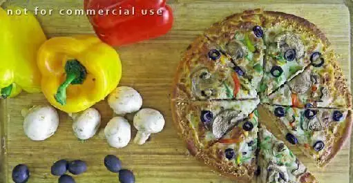 پیتزای خوشمزه با قارچ، زیتون و فلفل دلمه رنگی در کنار مواد اولیه تازه شامل فلفل دلمه زرد و قرمز و قارچ در محیط فست فود دی.