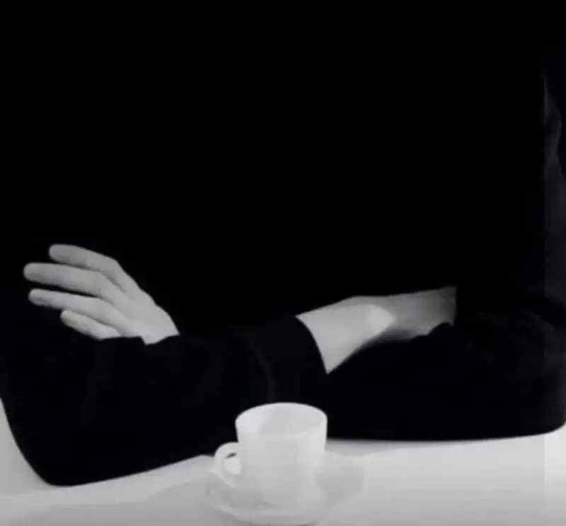 لحظات آرامش‌بخش در کافه سامیا: فردی با بازوهای گره‌خورده و فنجان قهوه، مکانی دلنشین برای تجربه بهترین طعم قهوه.