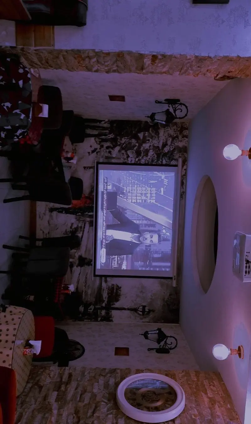 تصویری از فضای داخلی دلنشین کافه شاپرک با دکوراسیون خاص سنگی، دیوارهای طرح‌دار و نورپردازی گرم، محیطی آرامش‌بخش مجهز به پروژکتور.