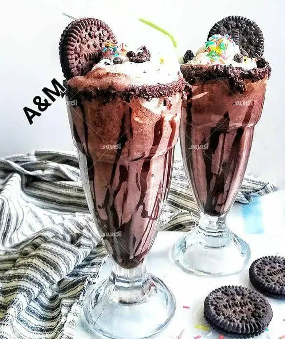 دو میلک شیک شکلاتی خنک و خوشمزه با اورئو، خامه و سس شکلات در کافه A&M، انتخابی عالی برای نوشیدنی دسر.