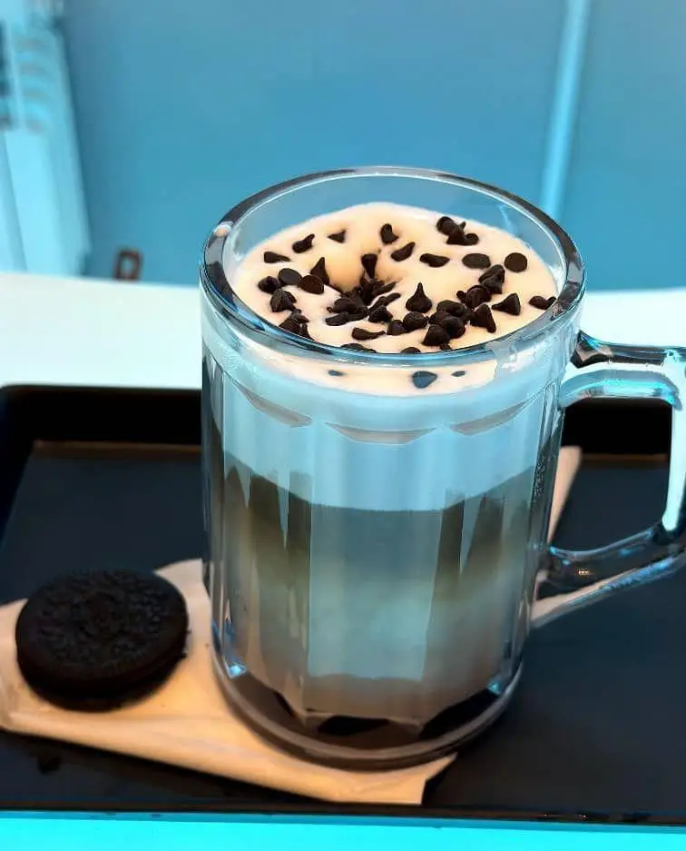 نوشیدنی لاته با فوم شیر و شکلات چیپس در کافه قلیان عربی A&M، همراه با کوکی اوریو، تجربه‌ای آرامش‌بخش و دلچسب.