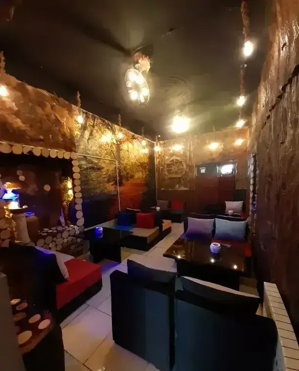 فضای داخلی دنج کافه قلیان عربی A&M با دکور روستیک، نورپردازی گرم و مبلمان راحت برای تجربه ای آرامش بخش.